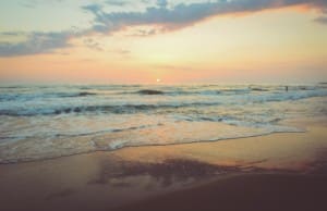 A sunset on a beach, a yellow sky with a blue ocean