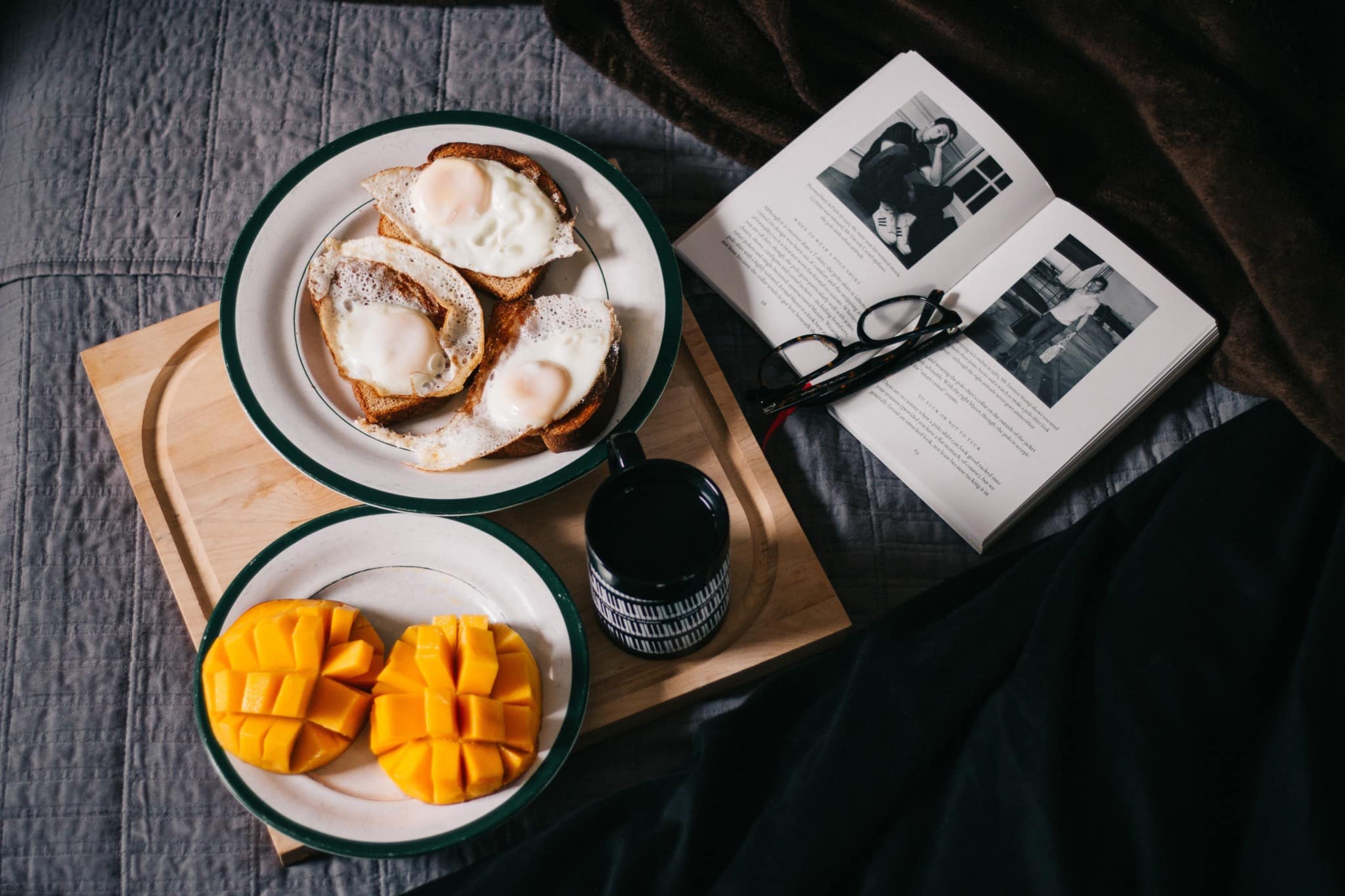 Breakfast Spread sliced mangos, eggs, and bread on bed